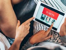 Two female friends drinking coffee and shopping online