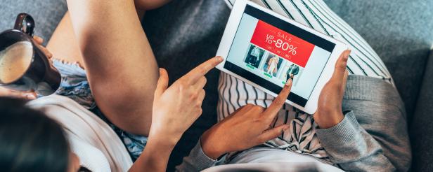 Two female friends drinking coffee and shopping online