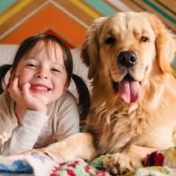 Young girl playing with dog on a bed