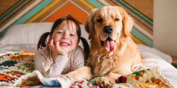 Young girl playing with dog on a bed