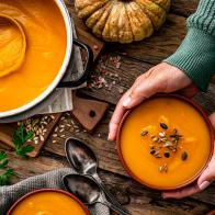 Woman serving two bowls of pumpkin soup for Thanksgiving meal