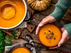 Woman serving two bowls of pumpkin soup for Thanksgiving meal