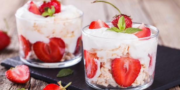 Eton Mess - Strawberries with whipped cream and meringue in a glass beaker. Classic British summer dessert.selective focus