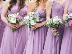 Bridesmaids in pink and vioilet dresses holding floral arrangements. CLose up of bridal party with bouquets.