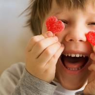 enfant heureux avec bonbons en forme de coeur devant les yeux