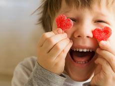 enfant heureux avec bonbons en forme de coeur devant les yeux