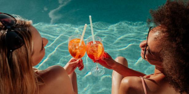 Female friends at a poolside summer party enjoying cocktails