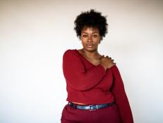 Portrait of african american woman standing against white background. Plus size female in casual clothing looking at camera.