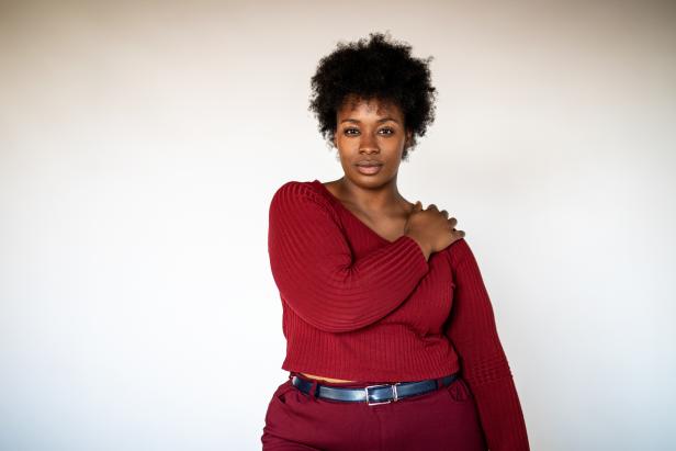 Portrait of african american woman standing against white background. Plus size female in casual clothing looking at camera.