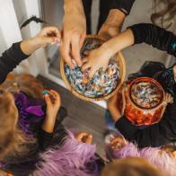 Children happy to receive many sweets and gifts. All girls wearing in bright witch of fairy dresses. Happy childhood. American traditional culture of Halloween celebration. Top view, copy space background with unrecognizable people.