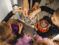 Children happy to receive many sweets and gifts. All girls wearing in bright witch of fairy dresses. Happy childhood. American traditional culture of Halloween celebration. Top view, copy space background with unrecognizable people.