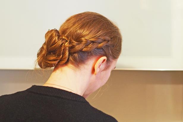 Young Italian woman with red hair, head and shoulder close-up, with very personal elaborate hairstyle, against neutral background.