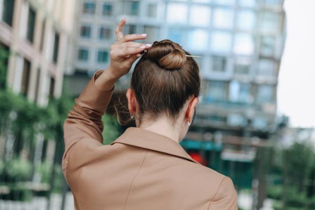 Mid Adult Elegant Female Manager Wearing Fashionable Beige Suit Jacket Standing Against Modern Office Exterior Background. Back View, Ambient Light, Copy Space