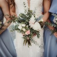 Bride and bridesmaids in blue dresses with bunches of white roses