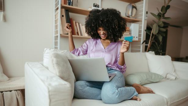 Happy woman with credit card doing online shopping on laptop at home