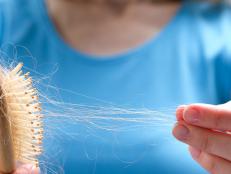 A woman holds a wooden comb in her hands, cleans it of fallen hair after combing. The concept of head health problems, deficient conditions in the body due to stress and depression, a consequence of chemotherapy and radiation for cancer.