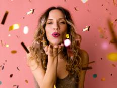 It's party time: A cheerful attractive Caucasian female in glitter brown dress sending kisses while looking at camera. (studio shot, pink background)