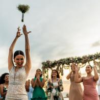 Bride throwing the bouquet to her friends on the beach wedding party