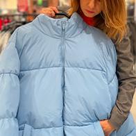 Caucasian beautiful mature female buying outdoor clothes looking at down jacket in store. Pretty happy lady buying outerwear in city mall at season sale. Fashion clothes. Shopping concept