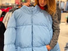 Caucasian beautiful mature female buying outdoor clothes looking at down jacket in store. Pretty happy lady buying outerwear in city mall at season sale. Fashion clothes. Shopping concept