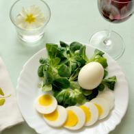 top view of a plate of corn salad and hard-boiled egg, whole and sliced, square format.