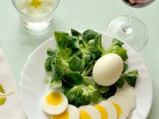 top view of a plate of corn salad and hard-boiled egg, whole and sliced, square format.