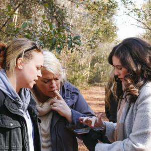 Madison, Janelle and realtor Elise look at a map of the farmland property on a phone.